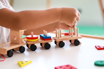 Cute little boy playing with wooden toys at table, closeup
