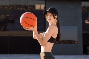Sporty young woman with cap and ball outdoors