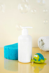 Obraz na płótnie Canvas Natural Hypoallergenic Foam for bathing children. White Plastic pump bottle. children's cosmetics. Bottles, towel and turtle toy and a washcloth with soap bubbles on yellow background. Copy space