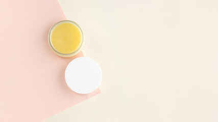 An open jar with Lanolin, a grease from sheep wool. Acts as a skin ointment, water-proofing wax, and for washing laundry. on a minimalistic pink background. Skincare concept. Copy Space. Top view