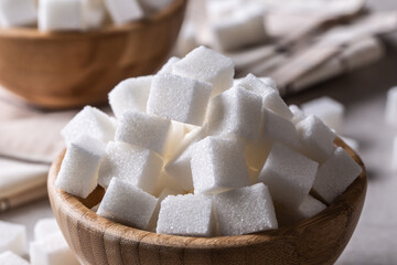 White sugar cubes in a wooden bowl on the table