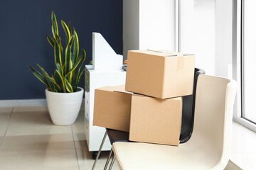 Cardboard boxes with belongings on chairs in office on moving day