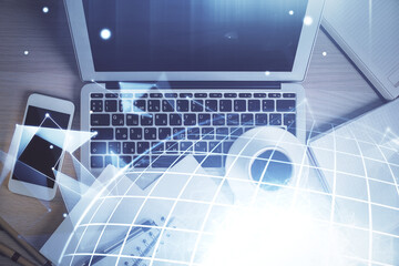 Double exposure of map hologram drawing over study table background with computer. Concept of international network. Top view.