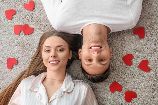 Happy couple lying on floor at home, top view. Valentine's Day celebration