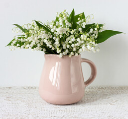 beige jug with a bouquet of lilies of the valley.
