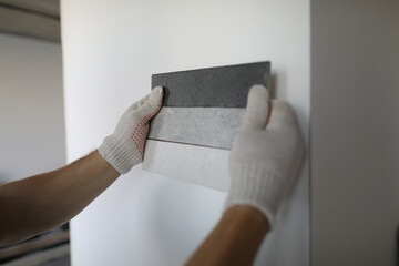 Male designer choosing tile for wall in apartment closeup