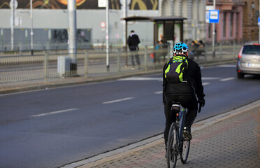Fototapeta na wymiar Mężczyzna na rowerze z plecakiem jedzie ścieżką rowerową w mieście Wrocław. 