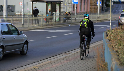 Fototapeta na wymiar Mężczyzna na rowerze z plecakiem jedzie ścieżką rowerową w mieście, Wrocław. 