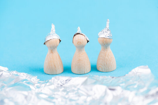 Three wooden figures wearing an alu hat, conspiracy theories, tin foil, symbolic