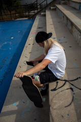 vertical top view of long-haired hippie man with his skateboard looking at his cell phone