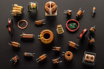 Inductors with a ferrite core, inductor copper coil, and also round RFID Antenna copper coil  on a black background, top view - obrazy, fototapety, plakaty