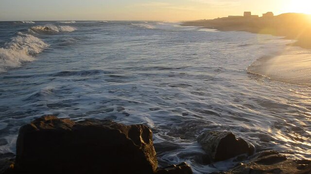 Atardecer dorado mirando las olas del mar desde la escollera. Olas de izquierda a derecha.