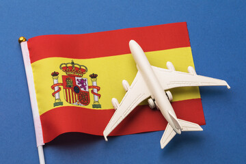 Spain flag and toy plane on blue background, concept on the theme of travel to Spain