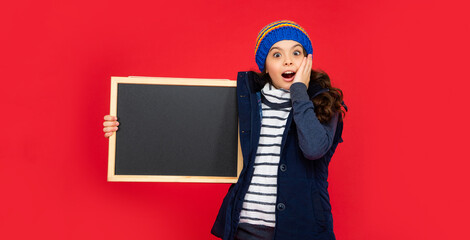 shocked teen girl holding chalkboard with copy space. child back to school. advertisement.