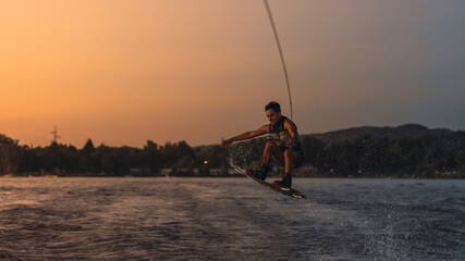 latino mas doing wakeboarding in a lake with mountains in the background