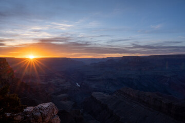 Fototapeta na wymiar Purple Sunset with Orange Sunburst over the Grand Canyon