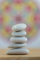 Stone cairn on white and colorfull red yellow mandala background, five stones tower, simple poise stones