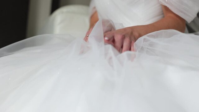 The hand of the bride holds on to the dress.
