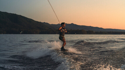 latino mas doing wakeboarding in a lake with mountains in the background