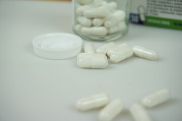Glass jar and white pharmacy capsules