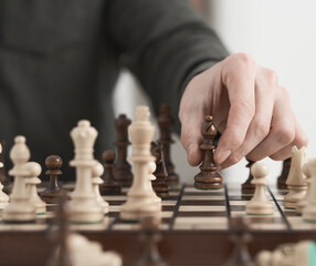 Chess game. The young player makes a move with the queen-officer piece. Wooden chess chessboard brown color. Game of chess

