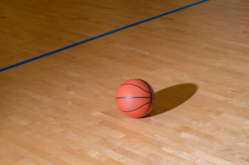 Basketball on hardwood court floor with natural lighting. Workout online concept. Horizontal sport theme poster, greeting cards, headers, website and app