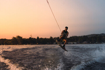 latino mas doing wakeboarding in a lake with mountains in the background