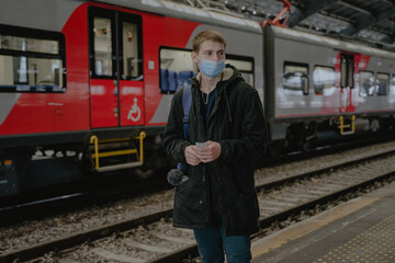 a guy in a mask stands on the platform by the train