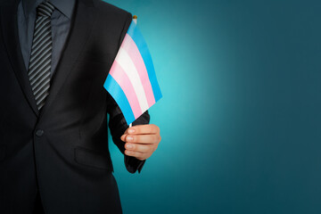 Businessman hand holding flag in transgender pride colors.