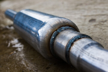 part of a muffler on a concrete floor, close up