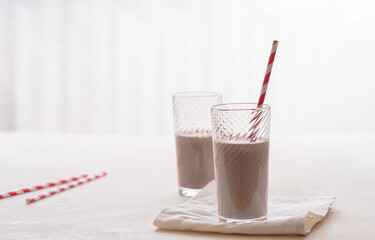 Coffee drink with milk in glass glasses. White-red paper tubes. Light table. Place for your text.
