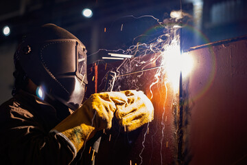 The welder welds metal structures by manual electric arc welding. MMA welding.