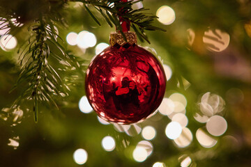 A red Christmas tree decoration with the photographer visible in the reflection. In the background...