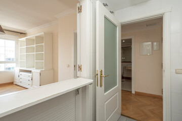 Empty room with aluminum window, white aluminum radiator and wardrobe with mahogany doors and gold handles