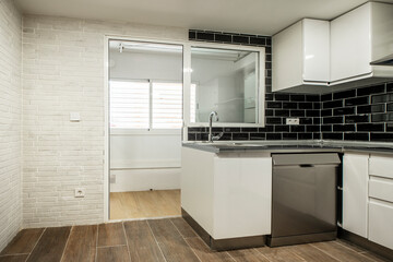 kitchen with white cabinets white brick wall black tiles and aluminum appliances