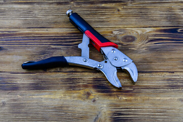 Locking pliers with red handles on a wooden background