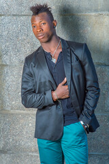 Dressing in a black blazer, green pants,  a hand in his pocket, a hand putting on his chest, a...