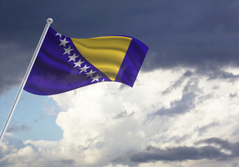 Flag of the Bosnia and Herzegovina on a stick, dark clouds in the background