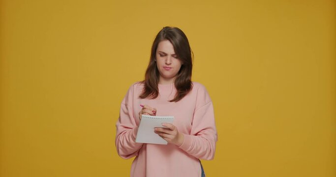 Pensive creative young girl writing in notebook, making notes planning, laughing, coming up new ideas, feel inspiration