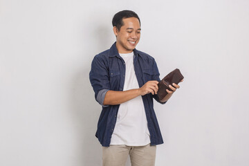 Portrait of cheerful handsome asian man looking inside his wallet isolated on white background 