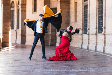 Man and woman in flamenco costume performing a dance outdoors - obrazy, fototapety, plakaty