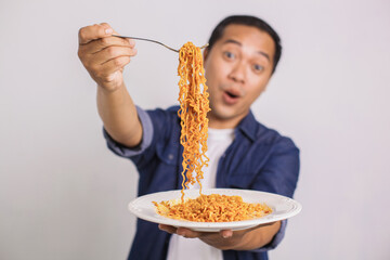 Asian man eating instant noodle and feel surprise with how delicious it is