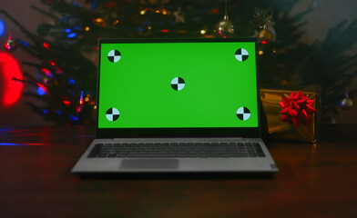 Laptop with christmas tree and gift. Green chroma key for your advertisement.