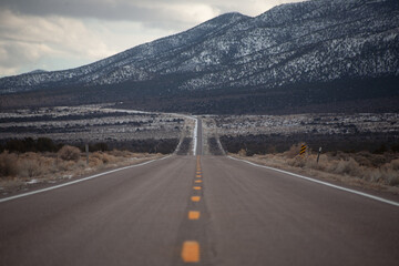 Naklejka premium On an empty stretch of highway , no cars in site. Ahead you can see the snowy mountains.