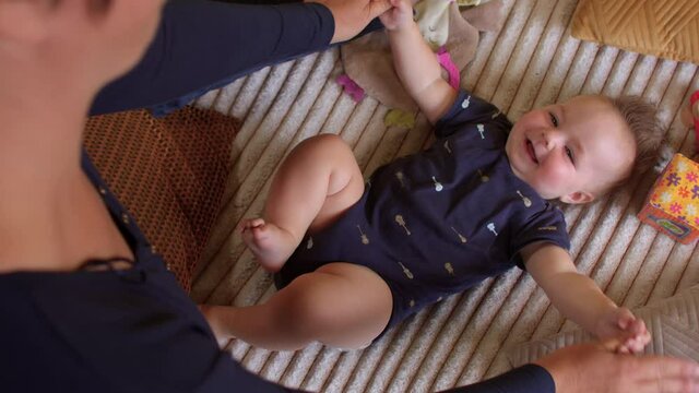 Gymnastics for a happy toddler baby. Mom makes movements with the hands of the child. Poor muscle tone also called hypotonia in babies could be a sign of AADC deficiency.. Parental care for child. 