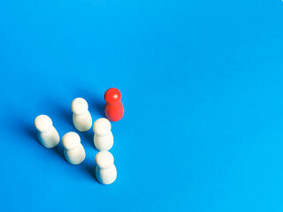 Wooden figures lead by red color against blue background. Unity and leadership concept
