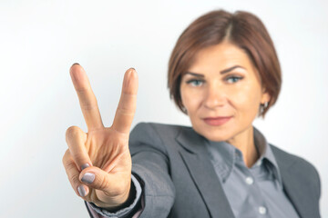 Business woman in suit shows victory sign with hand