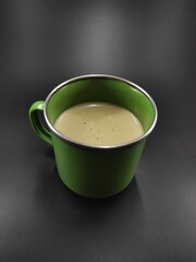 Photo of a glass of green cup containing cappuccino coffee isolated on black background, Not Focus