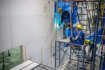 Construction company workers are drilling a wall to demolish and prepare for new construction.
