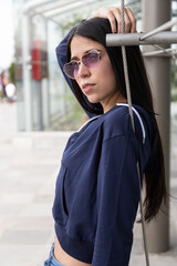 Fototapeta premium lifestyle of young latin girl with trendy long black hair posing relaxed in the city, wearing casual clothes and glasses, beauty and model